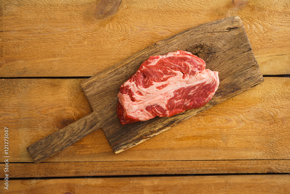 Uncooked chuck eye steak on wooden board Uncooked chuck eye steak on wooden board