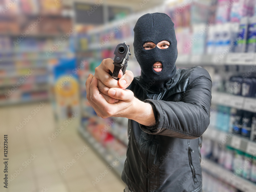 Robbery in store. Robber is aiming and threatening with gun in shop. Stock  Photo