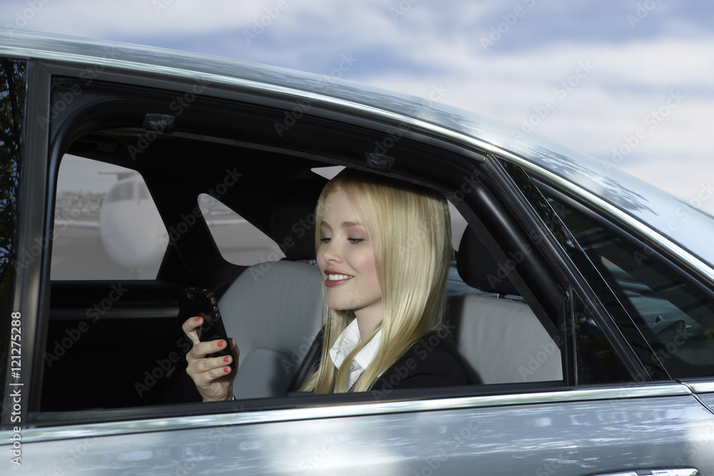 Naklejka premium Business Woman in car with mobile phone at airport