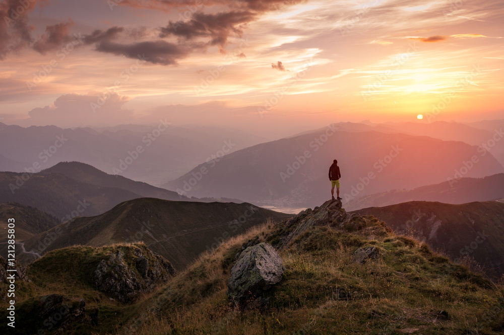 Man standing on a mountain summit at sunset