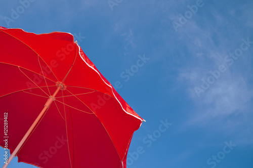 Red beach umbrella and blue sky. Summer beach vacations