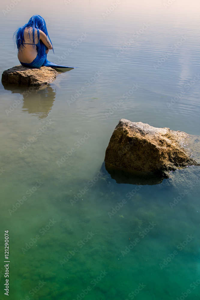 Traurige Meerjungfrau kauert auf Stein, daneben ein leerer Stein (hochkant)
