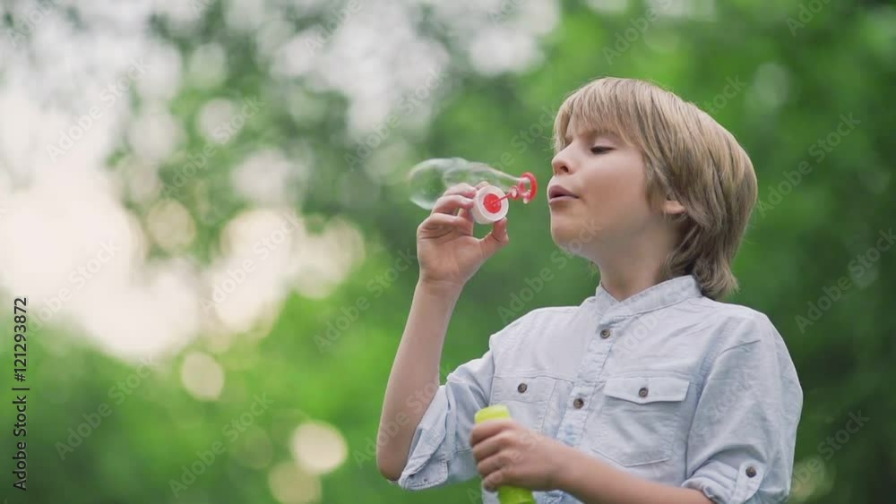 Happy boy blowing soap bubbles outdoors Happy boy blowing soap bubbles outdoors