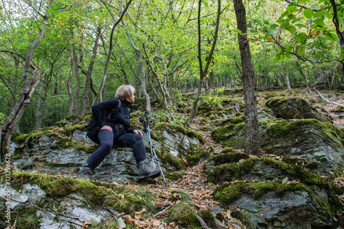 Seniorin wandern im Wald, sitzt auf einem Felsen blickt den Berghang hinauf, Denntal Eifel