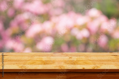 Empty wooden table with blurred pibk background.