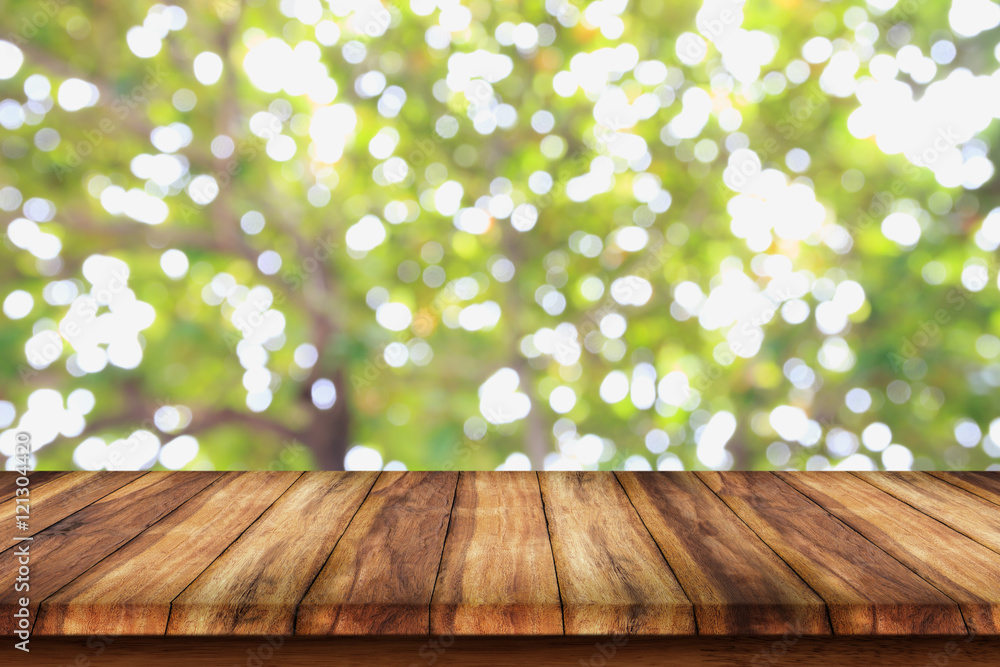 Empty wooden table with bokeh abstract green background.