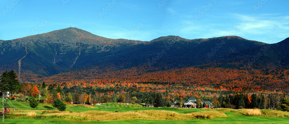 autumn mountain, colorful forest and green golf course at the foot of mountain