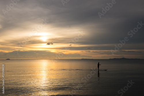 Silhouette of human rowing on the boat in ocean sea over dramati photo