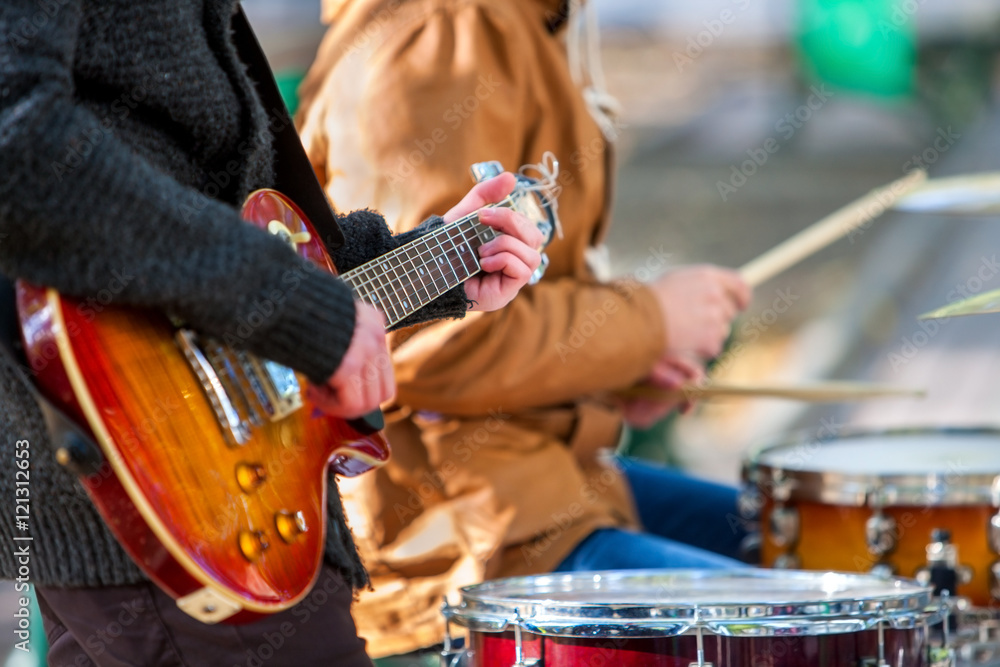 Fototapeta premium Muzyczni wykonawcy uliczni na zewnątrz jesienią. Środkowa część korpusu z gitarą.