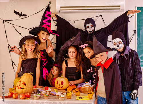 Halloween party with group children holding trick or treat in Halloween interior.Two adult in Halloween costume.