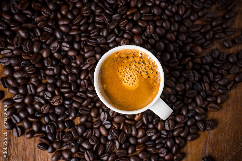 Fototapeta premium Coffee cup and coffee beans on wooden background. Top view.