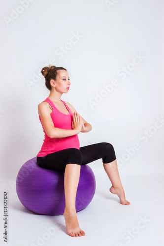 pregnant woman practicing yoga on a light background