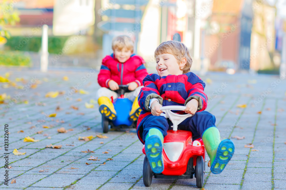 Two little kids boys playing with toy cars, outdoors Two little kids boys playing with toy cars, outdoors
