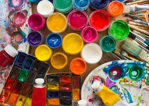 Colorful paints, brushes, palette on the wooden background. The workplace of the artist. Banner for the school.