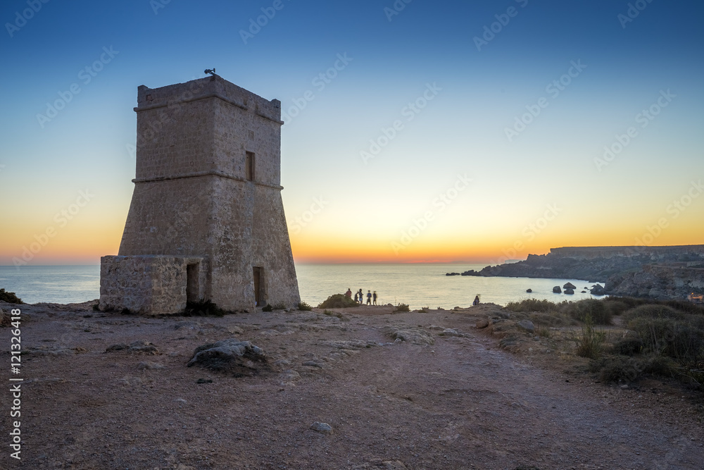 Malta, Ghajn Tuffieha Tower at sunset with tourists and clear blue sky at Golden Bay