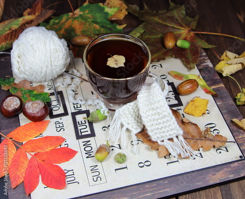 чашка чая и осенним листом с вязаным шарфом на осеннем календаре