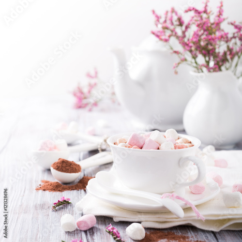 Cup of hot chocolate with mini marshmallows with cocoa on white wooden background with copy space.