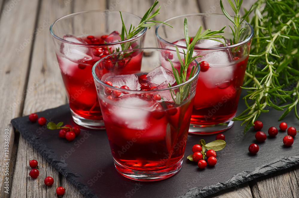 Refreshing drink with cranberries and rosemary on wooden background, selective focus Refreshing drink with cranberries and rosemary on wooden background, selective focus