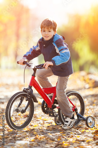 Happy boy with bicycle in the autumn park