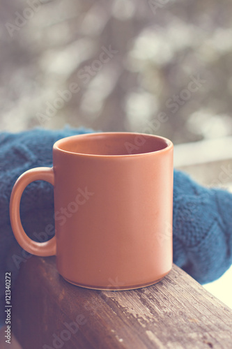 A cup with a hot drink on the background of the winter forest