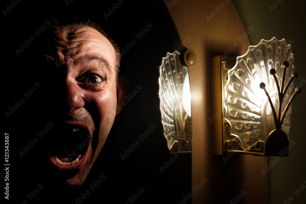 Fotka „The face of a screaming man in the mirror at night. Halloween