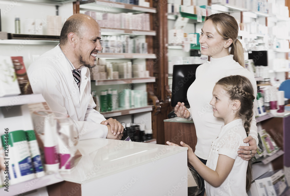 Laughing male pharmacist helping customers