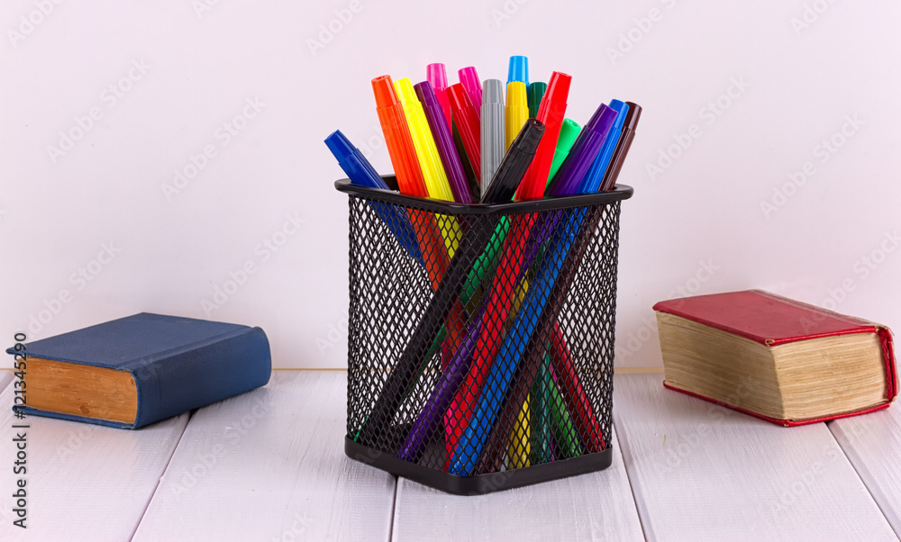 Fototapeta premium Multicolored markers in the stand next to small books