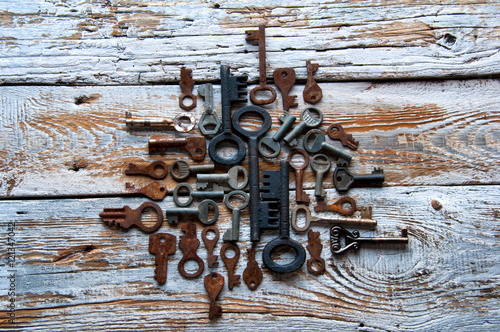 Many rusty keys and padlocks on white wood