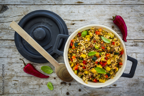 Tableau sur toile Millet groats with ground beef and vegetables and herbs in a pot on a wooden table