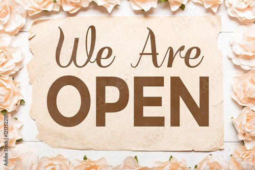 We Are Open concept. White roses frame and paper