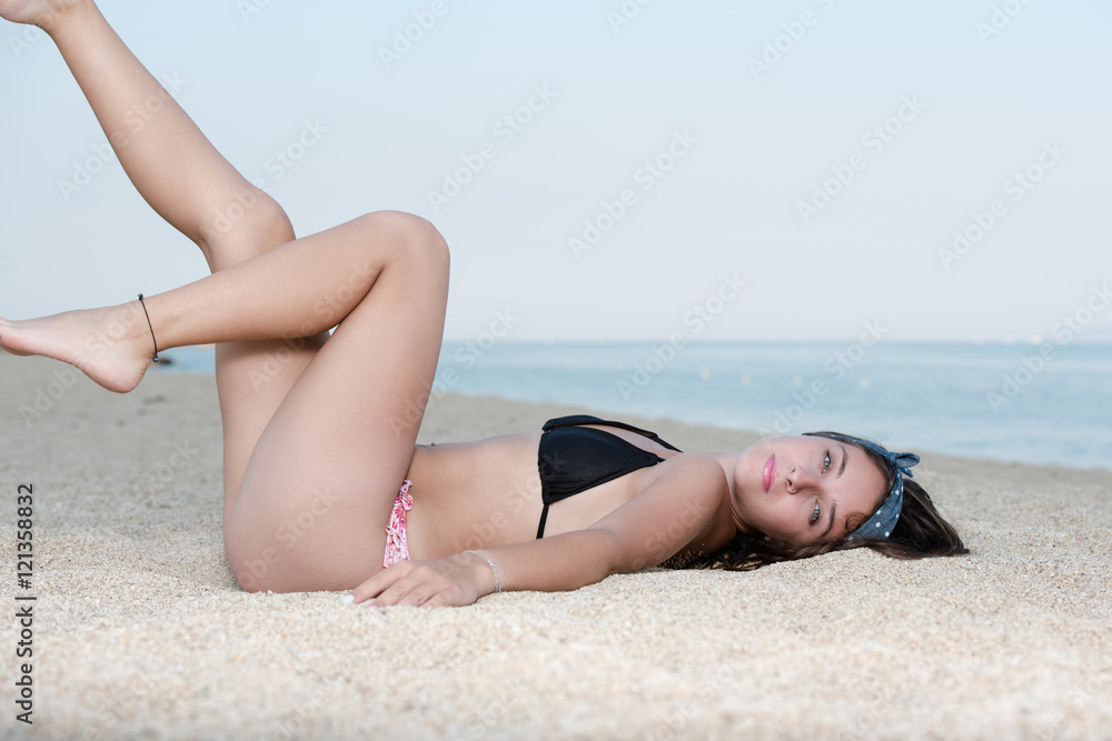 Pretty girl with great body, long hair and bow headband lying on the sand Pretty girl with great body, long hair and bow headband lying on the sand