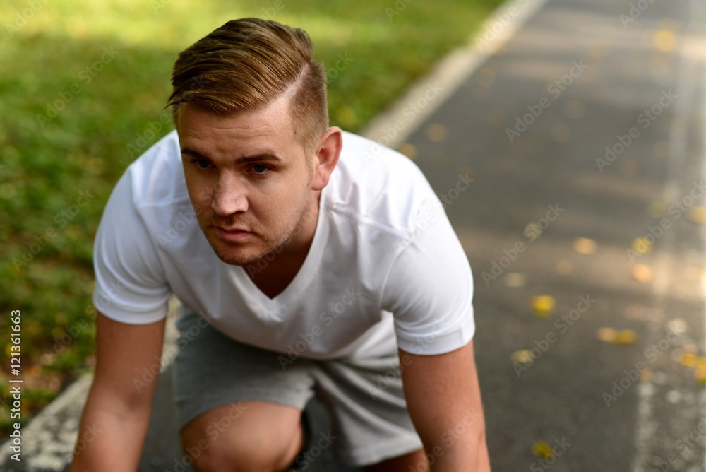 Blond man getting ready to run on a running track Blond man getting ready to run on a running track