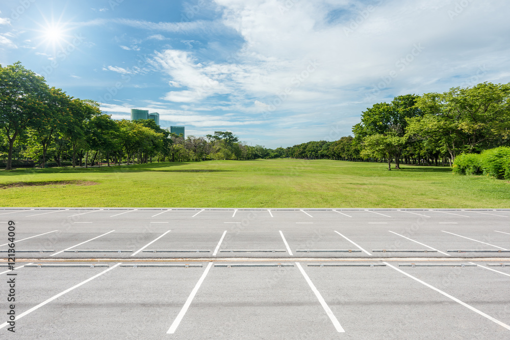 Empty parking lot against green lawn in city park Empty parking lot against green lawn in city park