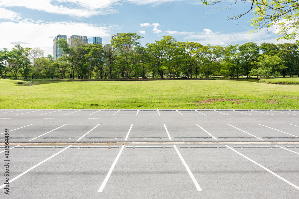 Obraz premium Empty parking lot against green lawn in city park