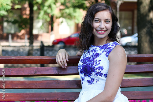 Beautiful young woman sitting on a park bench