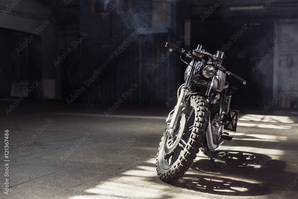 Obraz premium motocykl stojący w ciemnym budynku w promieniach słońca