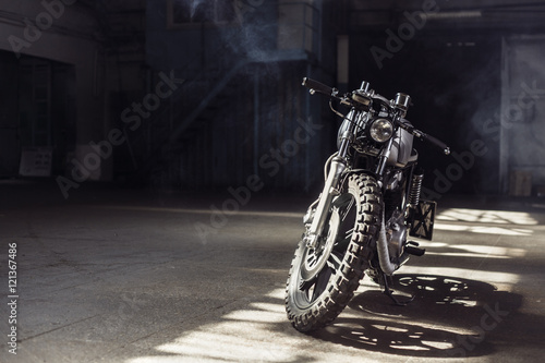 motorcycle standing in dark building in rays of sunlight photo