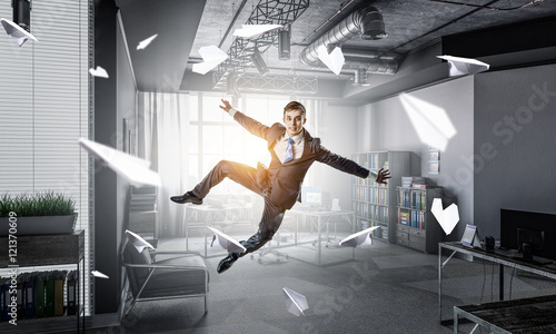 Jumping businessman in office . Mixed media