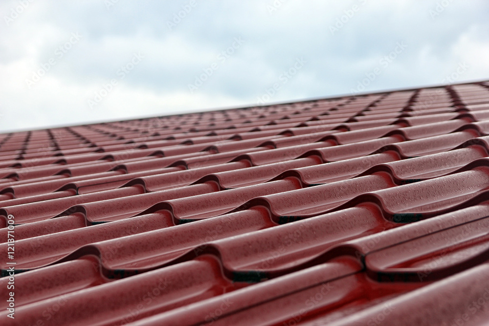 wet red metal roofing from sheet metal with droplets of rain clo