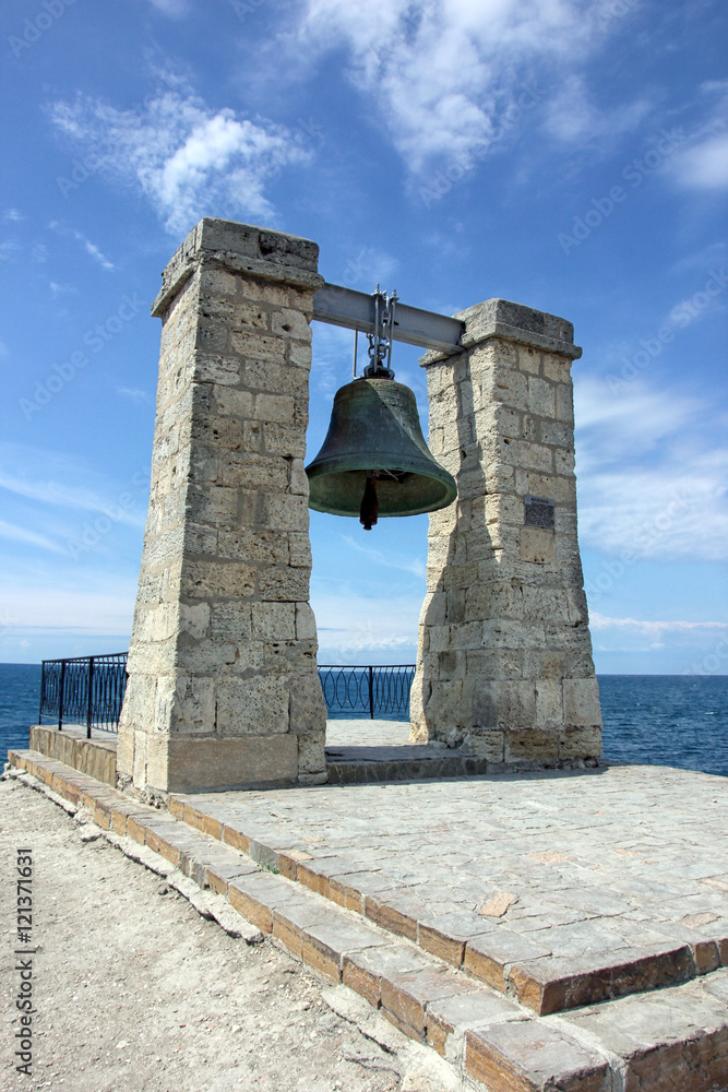 old large green bronze bell hanging on stone arch on the coast o