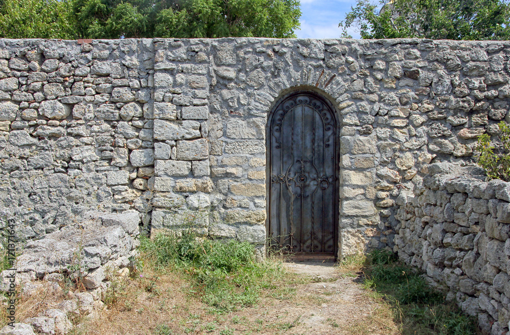 antique old black wrought iron door on rubble wall antique old black wrought iron door on rubble wall