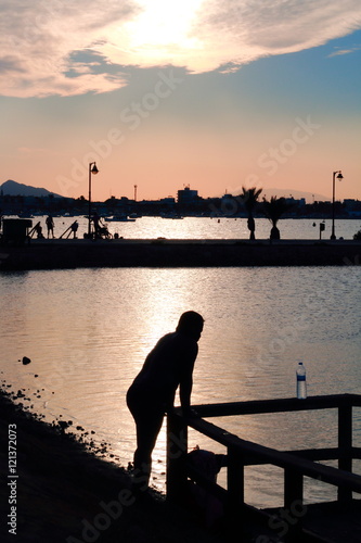 Silhouette of a man by the sea watching the sunset