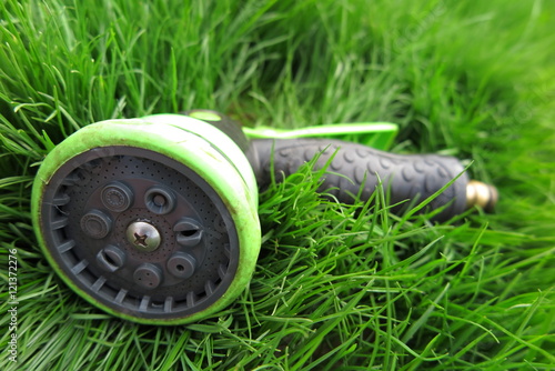 Adjustable shower (spray) lying on the fresh lawn grass in the summer garden photo