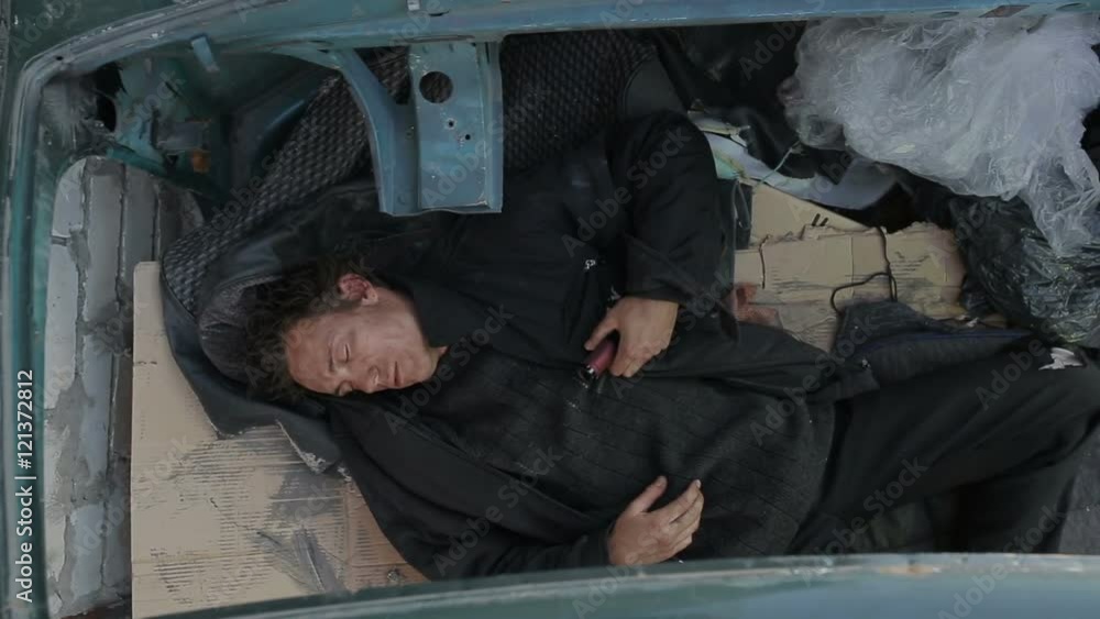 A homeless man sleeping in the car without a roof A homeless man sleeping in the car without a roof