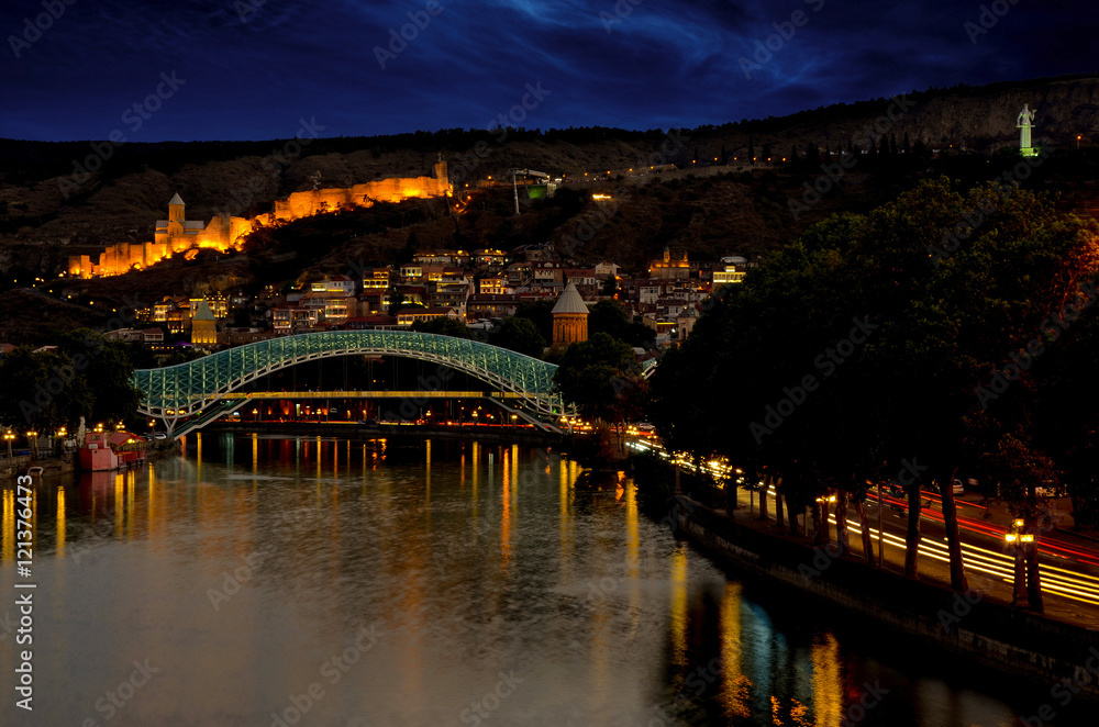 Tbilisi downtown. peace bridge made from glass, river Mtkvari, and famous ancient narikala fortress on hill. Night scene