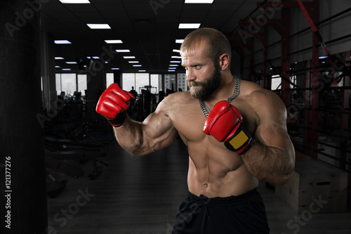 Strong muscular man boxing at the gym.