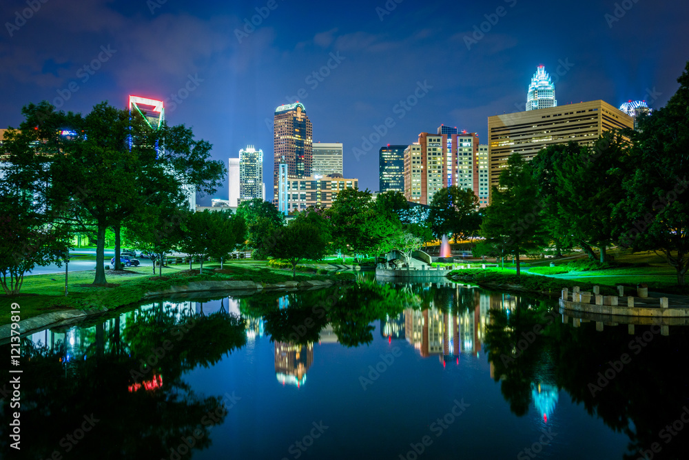 Fototapeta premium The Uptown skyline and a lake at Marshall Park at night, in Char