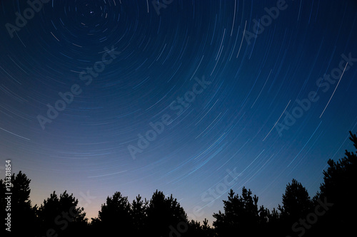  Star trail in the night sky. Against the background of tree cr