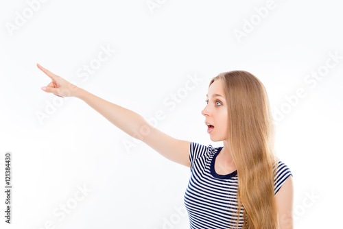 Shocked young woman pointing away on white background