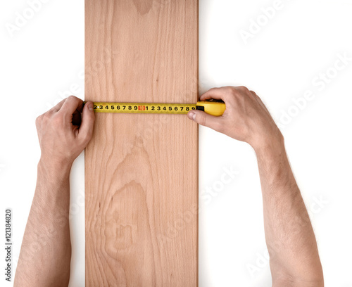 Man's hands measuring wooden plank with a tape line isolated on white background